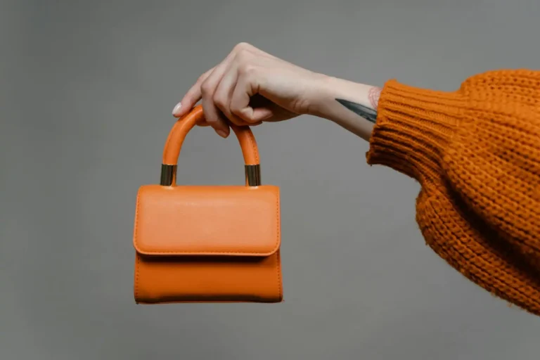 main de femme qui tient un mini sac à main orange